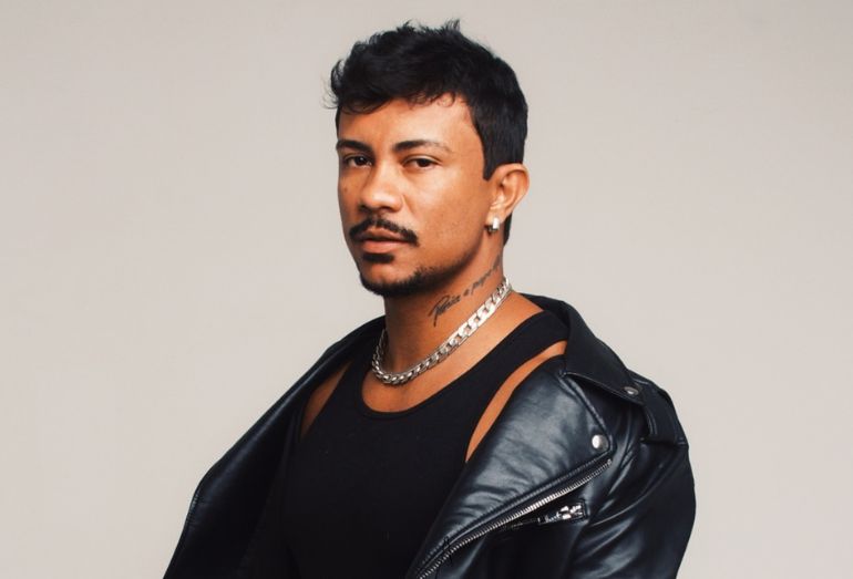 Foto de divulgação em estúdio do rapper Xamã, com estilo urbano e iluminação controlada, posando para promover sua nova turnê nacional.