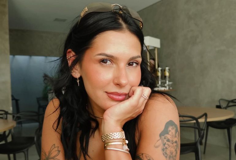 Ana Castela sorridente, usando seu chapéu de boiadeira, durante gravação em estúdio.