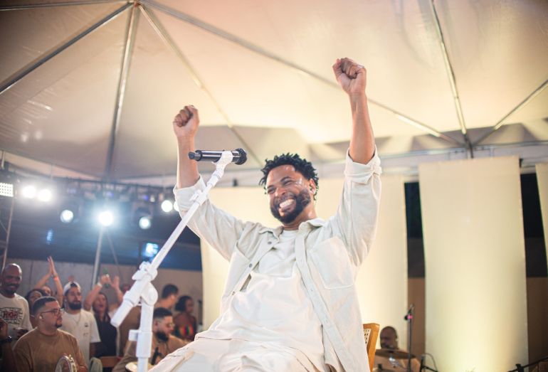 Julio Sereno cantando durante a gravação de seu audiovisual ao vivo, cercado por músicos.