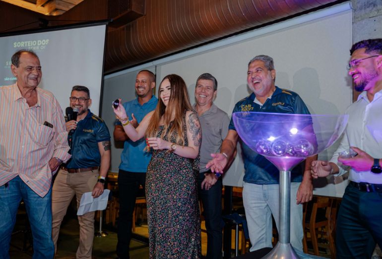 Integrantes de escolas de samba celebrando durante o sorteio da ordem dos desfiles da Série Ouro.