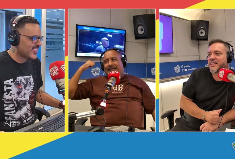 MC Mulato gesticulando e rindo ao microfone no estúdio da rádio FM O Dia enquanto conta sua história.